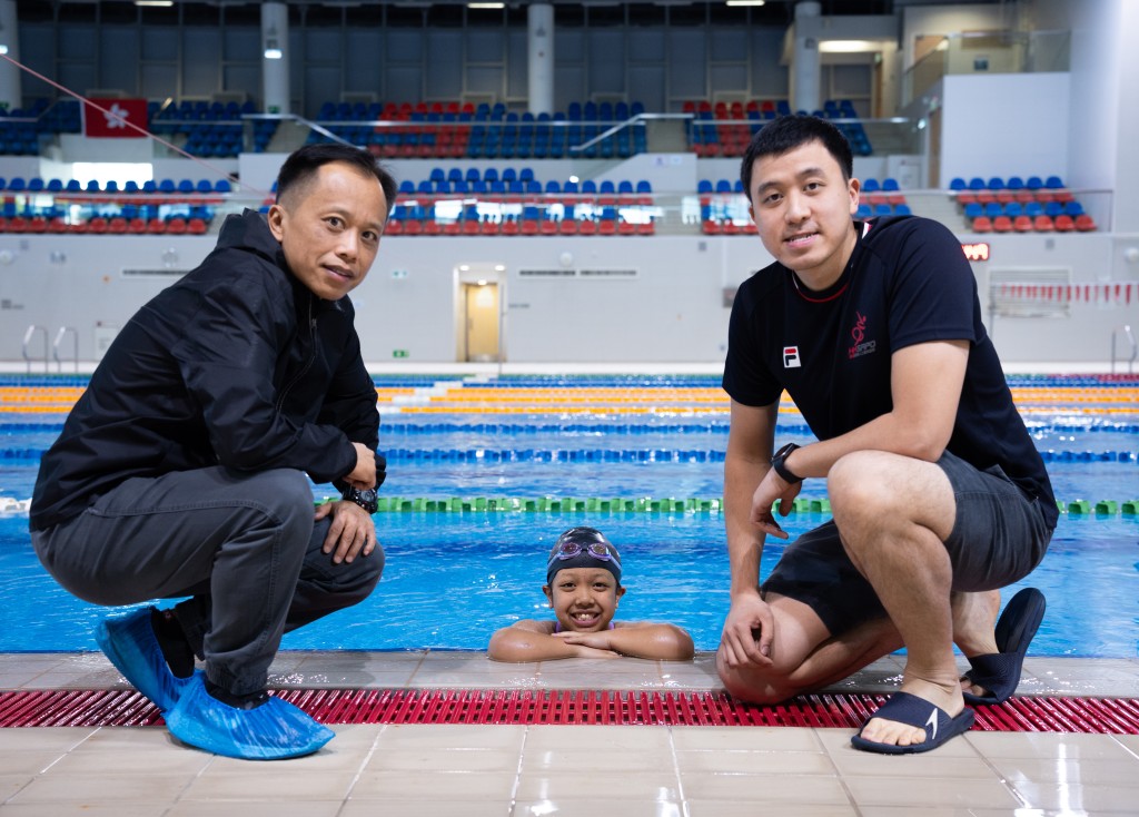 卓恩與父親（左）和教練江Sir在泳池邊合照。江Sir認為大家互相配合才能令到練習、比賽等各項事情更加順暢。（圖片來源：《親子王》）