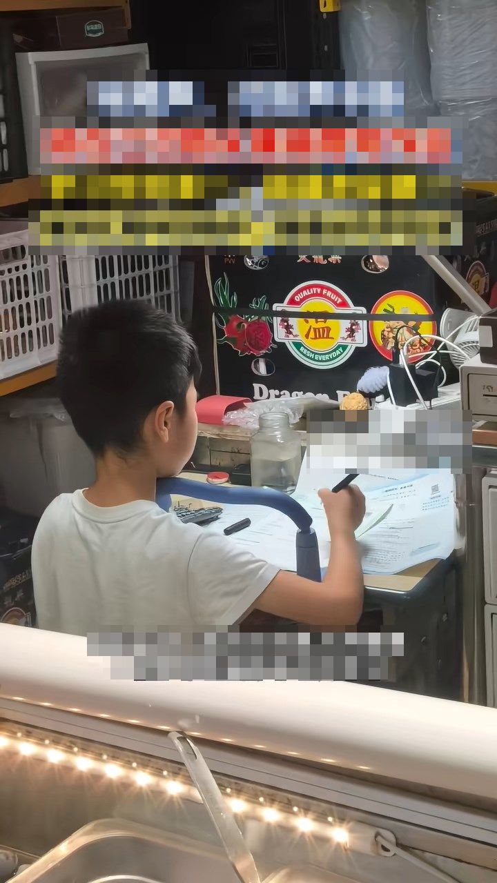 即使身处嘈杂的水果摊,男童仍专心温习功课。《湖北日报》 即使身处嘈杂的水果摊,男童仍专心温习功课。《湖北日报》