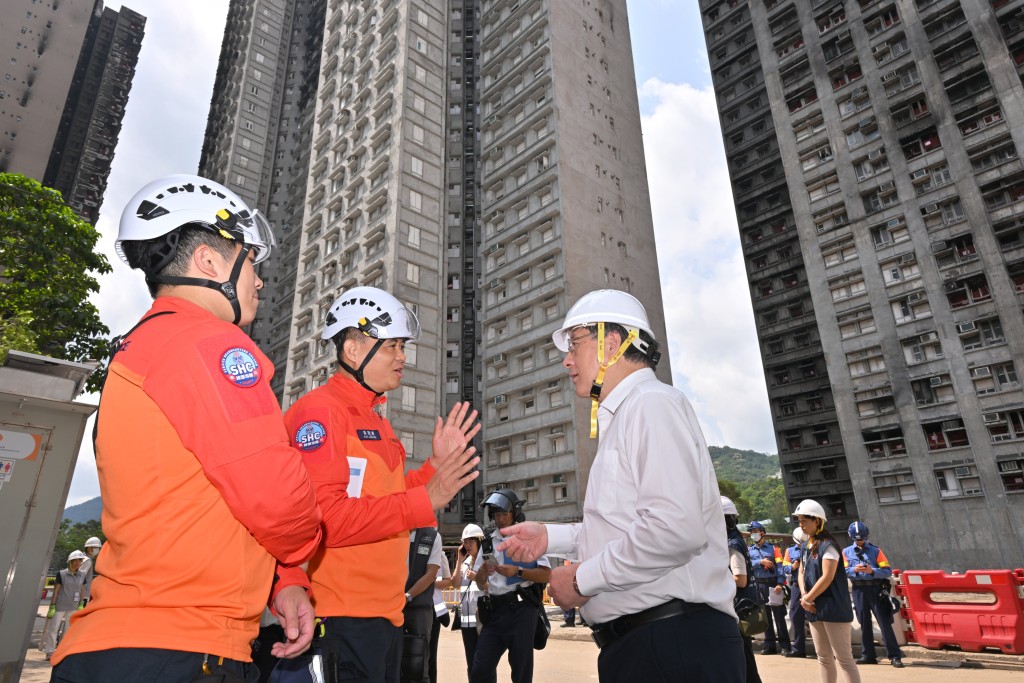 政務司副司長卓永興（右）今日到場視察宏福苑居民上樓安排，其間聽取民安隊總參事梁冠康（左）講述工作情況。