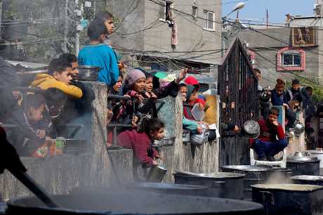 加沙南部拉法市一批巴勒斯坦儿童在等待领取慈善厨房烹制的食物。路透社