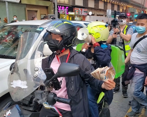 電單車司機手持大疊鈔票。資料圖片