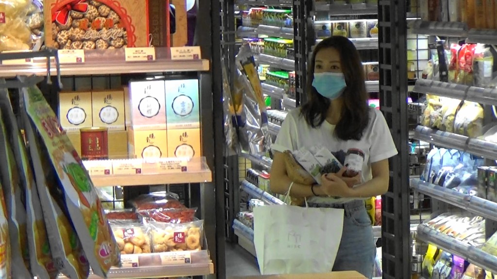 張寶兒用手捧住一堆食物慢慢行超市。