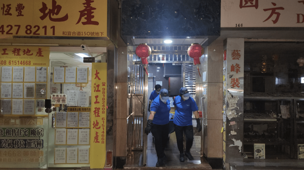 直至周日（17日）凌晨3时许，仵工从单位内舁走两具遗体。黎志伟摄