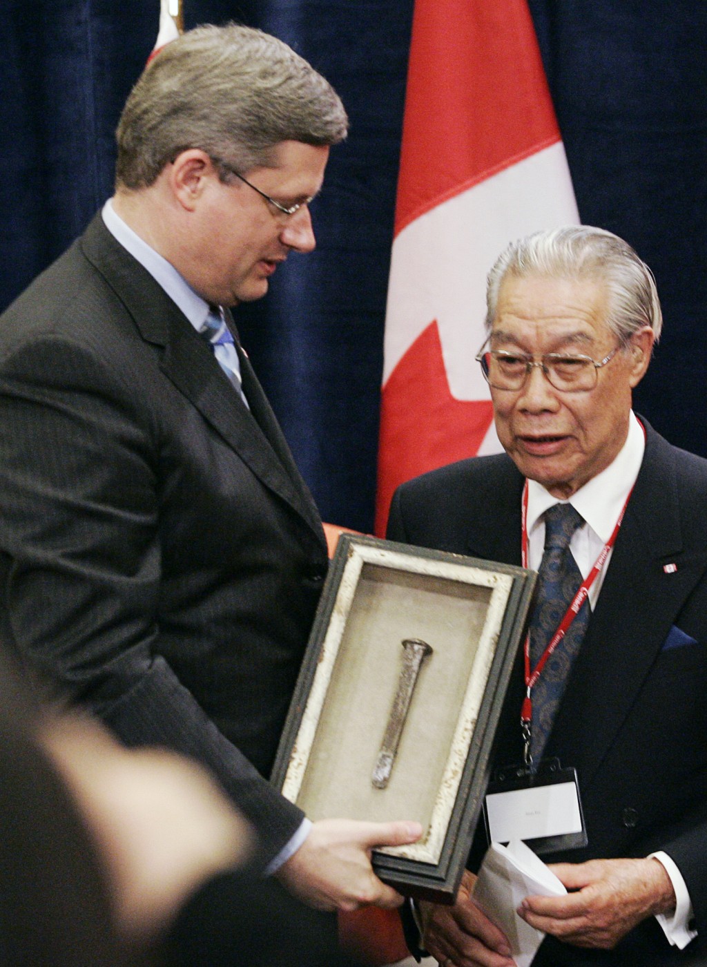 2006年,加拿大時任總理哈珀在渥太華舉行的政府正式道歉儀式上,從華人「人頭稅」倖存者 James Pon手上接過最後一根道釘。 美聯社資料圖 2006年,加拿大時任總理哈珀在渥太華舉行的政府正式道歉儀式上,從華人「人頭稅」倖存者 James Pon手上接過最後一根道釘。 美聯社資料圖