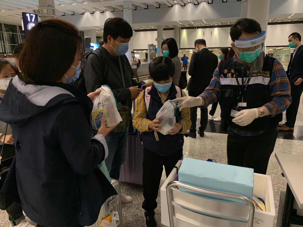 港人到達香港機場後，入境處職員為他們派發由航空公司提供的食物包。讀者提供