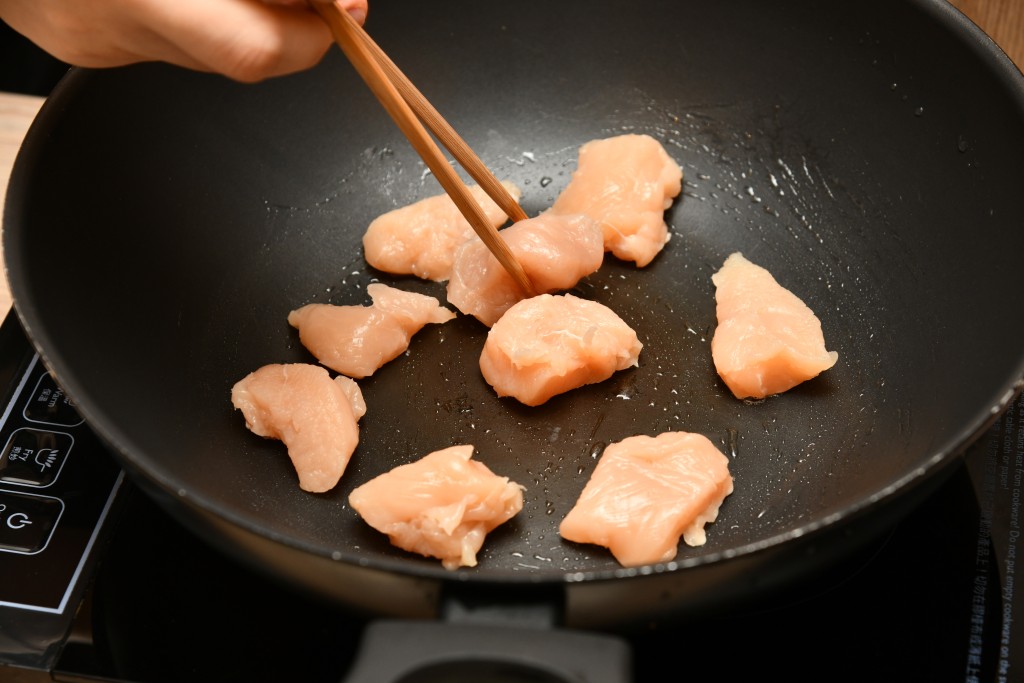Step 4: 鑊內燒熱油，煎熟雞件，盛起備用。 Heat oil in a pan. Stir-fry the chicken pieces until done, remove and set aside.