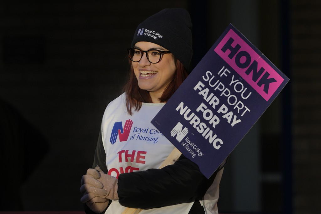 一名护士站在伦敦圣玛丽医院外的纠察线上，举著横幅。AP