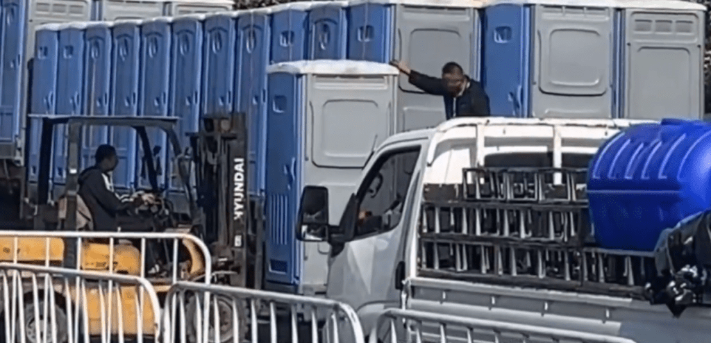 網片顯示,剷車從貨車上將流動厠所運下來。 網片顯示,剷車從貨車上將流動厠所運下來。