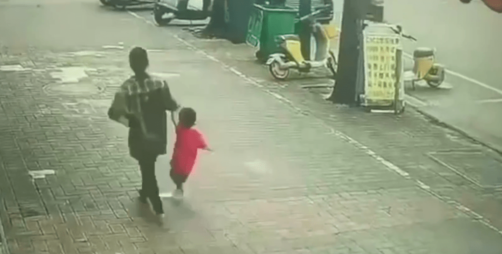 一名女子強行拖走一名小孩，小孩不停欲爭脫。