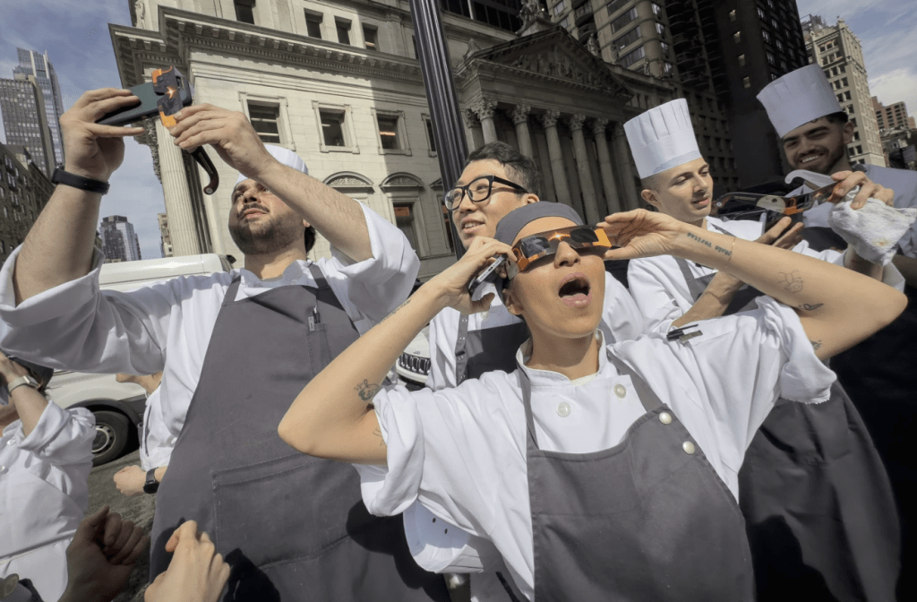 紐約，曼哈頓熨斗區的餐廳工作人員休息觀看日食。美聯社