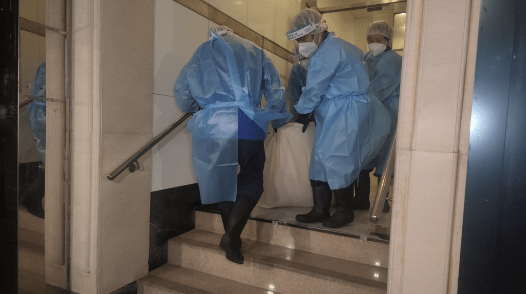 周四凌晨2時許,仵工將死者遺體從單位移走。黎志偉攝 周四凌晨2時許,仵工將死者遺體從單位移走。黎志偉攝