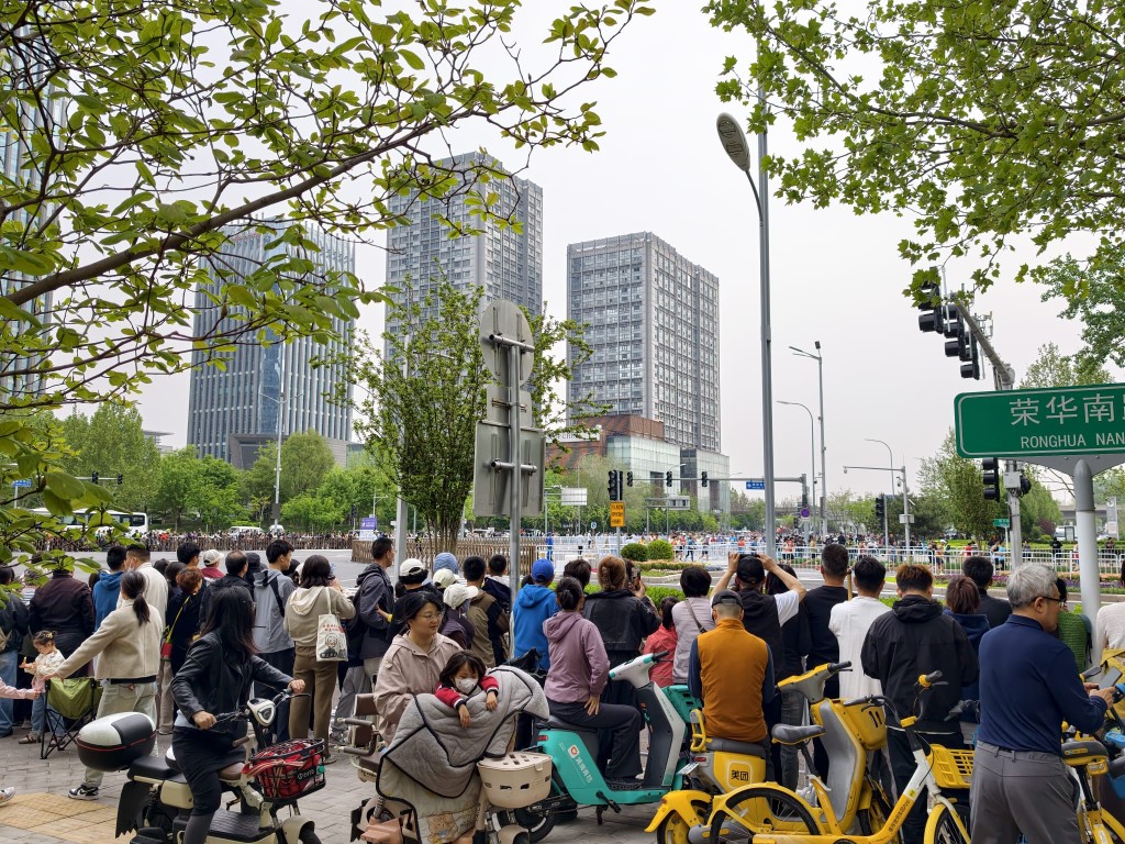 北京人形机械人半马19日早上开跑，大批市民围观。杨浚源摄