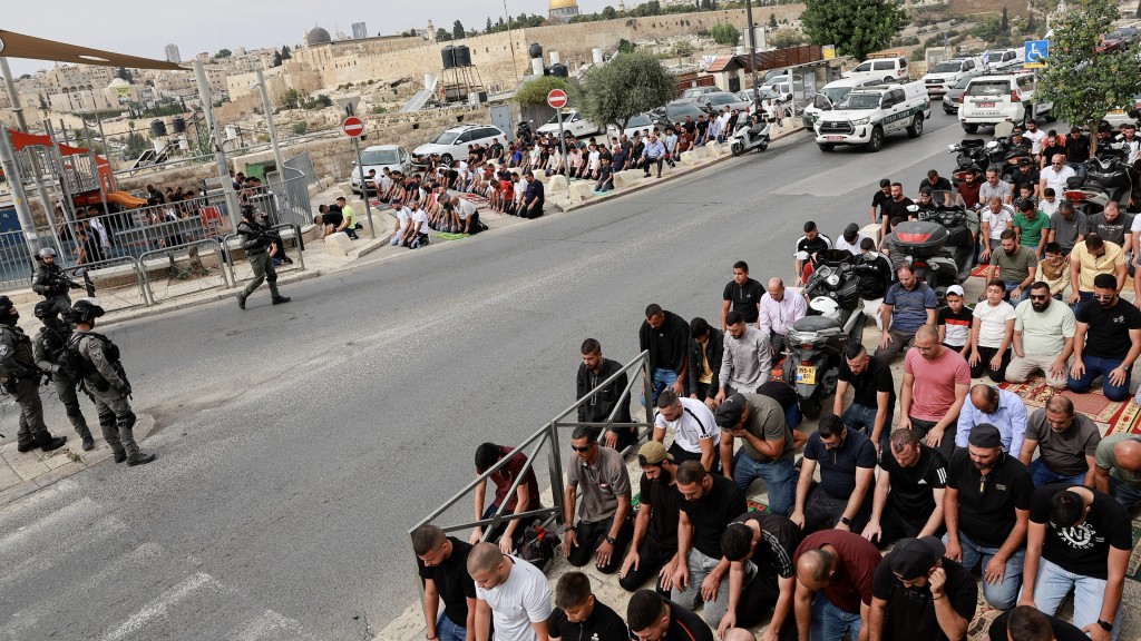 巴勒斯坦穆斯林在耶路撒冷舊城外的一條道路上舉行周五祈禱，以色列邊境警察站崗。 路透社