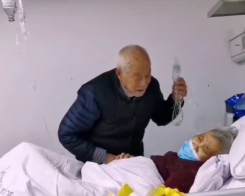 八旬夫妻雙雙感染新冠肺炎，丈夫吊着鹽水幫忙照顧妻子。(網圖)