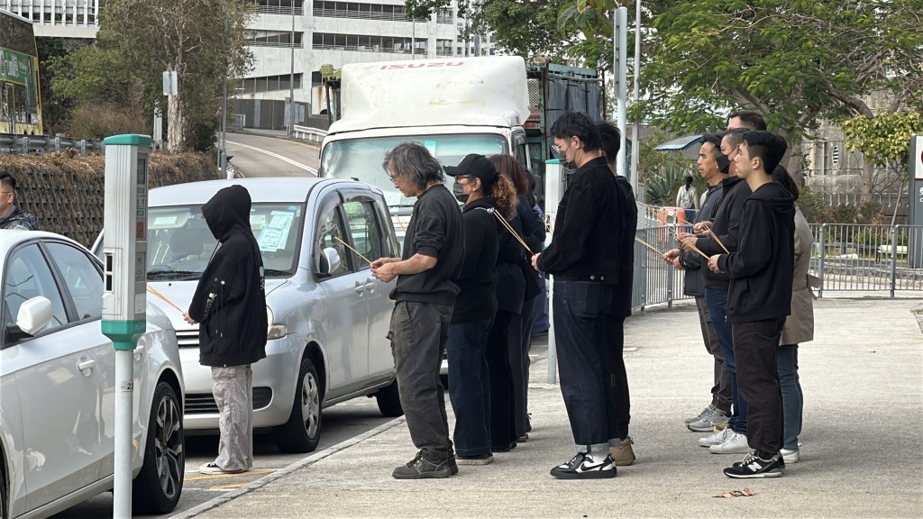 親友在道士帶領下上香，神情哀傷。