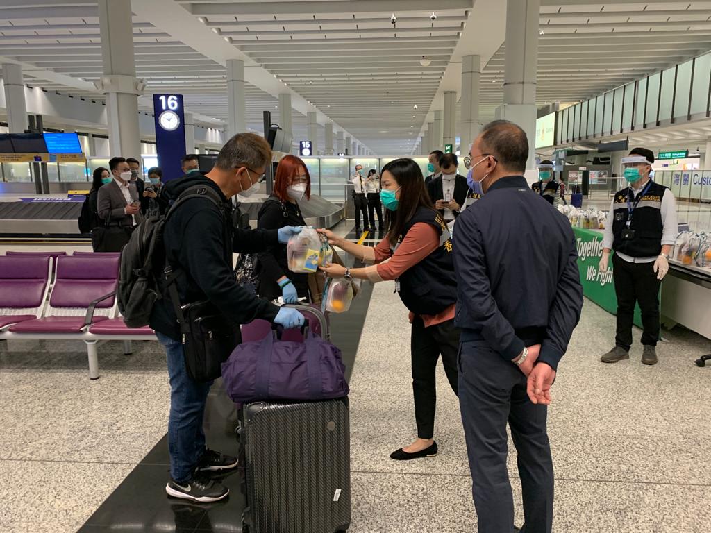入境處人員在香港機場為乘坐包機的港人送上由航空公司提供的食物包。