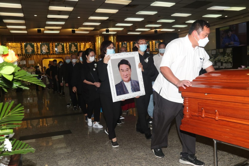 炳哥女兒譚淑瑩和譚廣銘一同捧着亡父遺照隨靈柩步出靈堂。