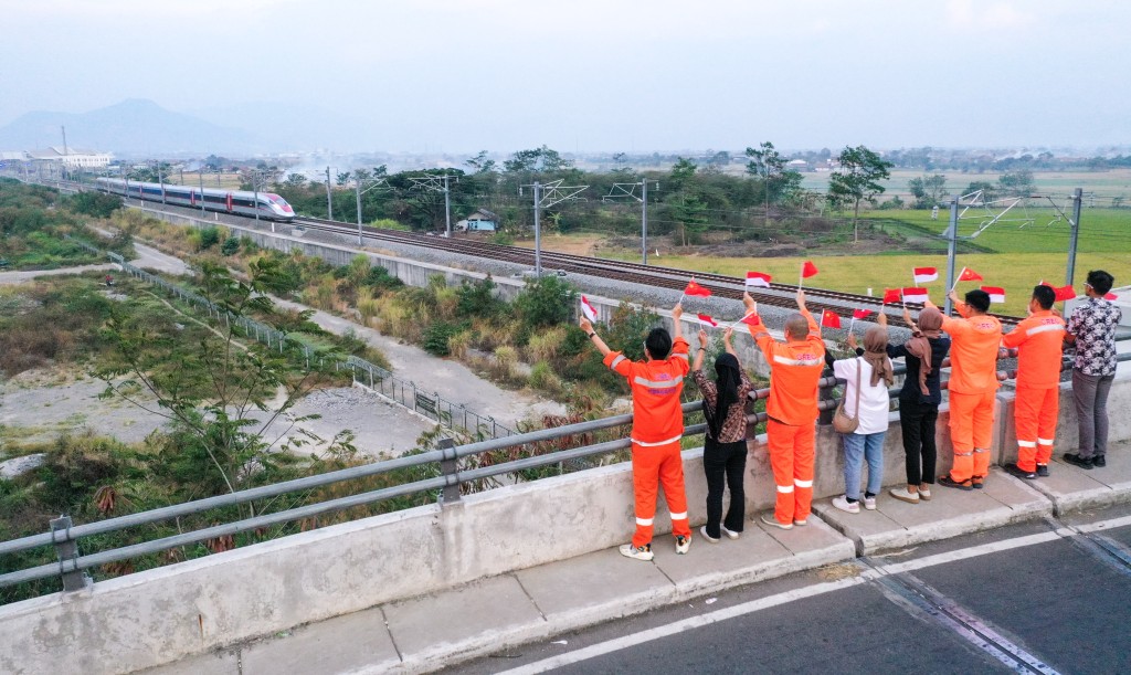 中鐵電氣化局的中國和印尼籍員工揮舞著中國和印尼兩國國旗，向遠處駛來的一列雅萬高鐵高速動車組列車歡呼。 新華社