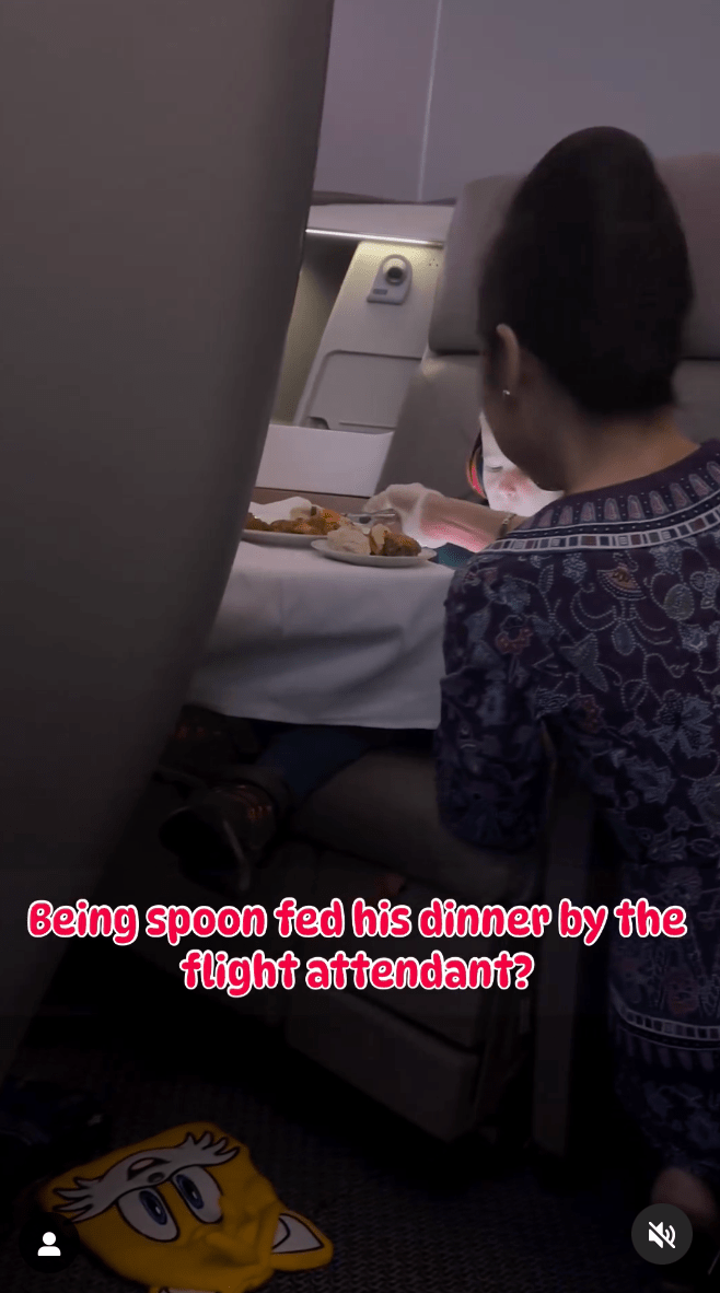 影片顯示，空姐戴着塑膠手套、蹲在他旁邊的走道上，用湯匙舀盤子裡的食物餵男童吃。