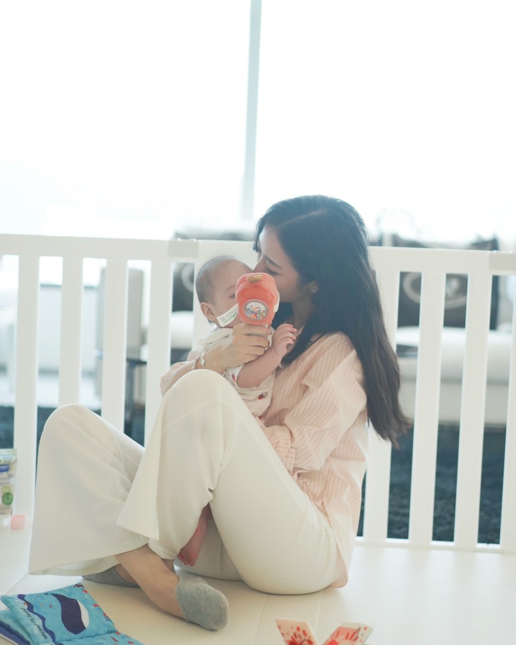 何依婷攬實女兒一邊玩着玩具，一邊錫錫女兒額頭，充滿着愛。