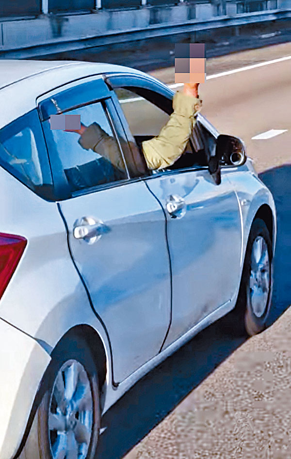 司機單手駕車，右手伸出窗外舉中指。