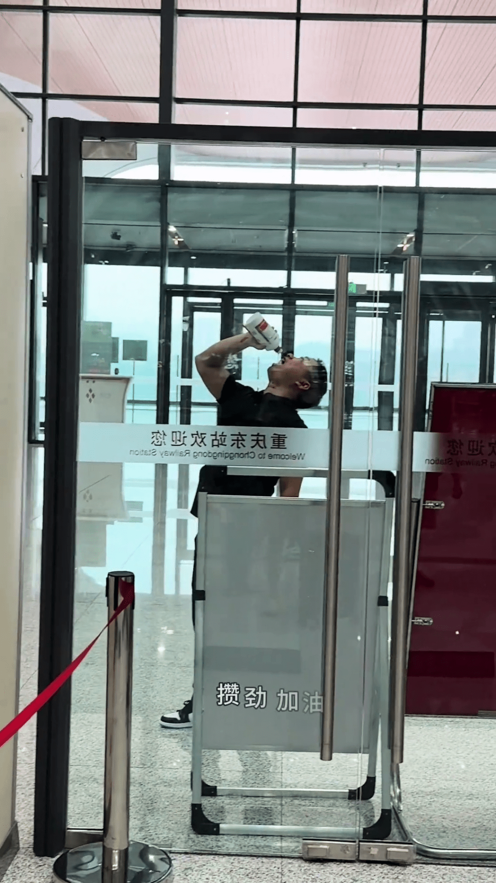 男乘客在安檢旁一口接一口的將整瓶茅台喝了。
