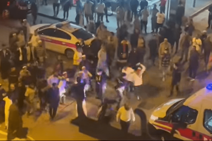 白衣南亞漢被帶上警車，後面有同鄉揮動支狀物體追趕，被警員制止。  fb香港突發事故報料區