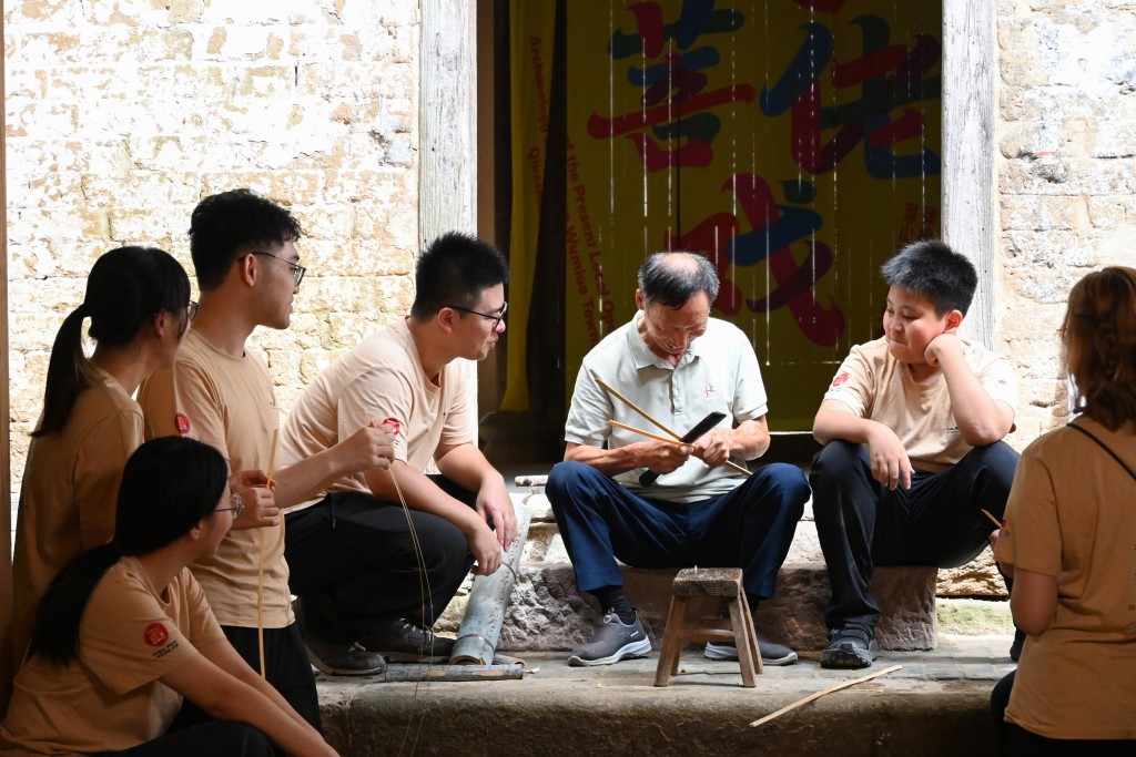 學生跟老藝人程從枝師傅（右二）學習竹編。