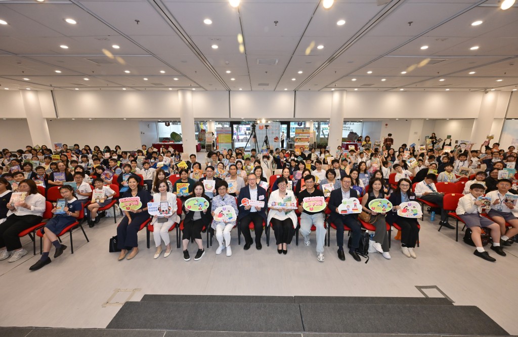 香港公共圖書館於4月23日與不同持份者合作設立「共讀點」，舉行「共讀半小時」活動。康樂及文化事務署助理署長（圖書館及發展）李子俊（前排左7）、公共圖書館諮詢委員會主席羅乃萱（前排左6）、香港學校圖書館主任協會會長黃毅娟（前排右7）與中小學生合照。