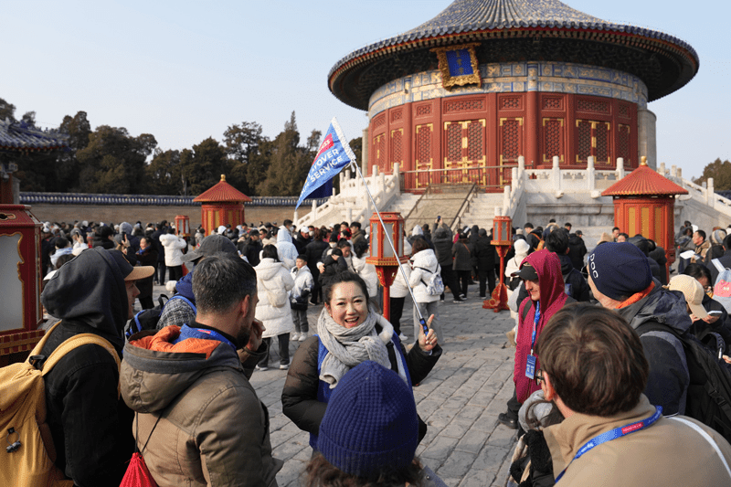 在北京天壇公園，導遊張賽（中）為外國遊客講解天壇和中國春節習俗。 新華社