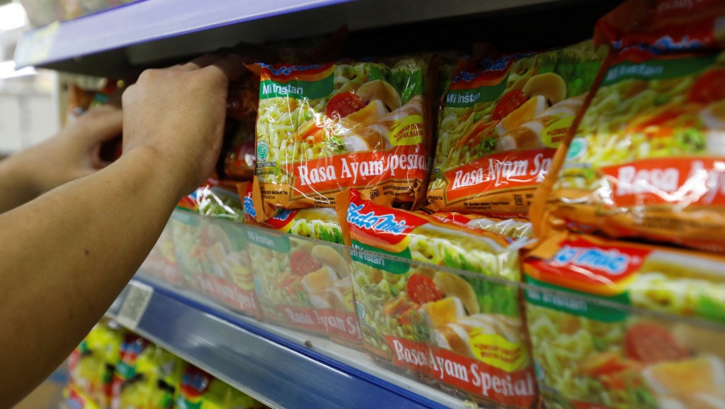 耶加达一名超市职员将特色鸡肉风味「营多」（Indomie）放上货架。 路透社