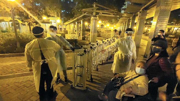 警員及政府工作人員在元州邨元盛樓拉起圍欄,進行需圍封強檢。