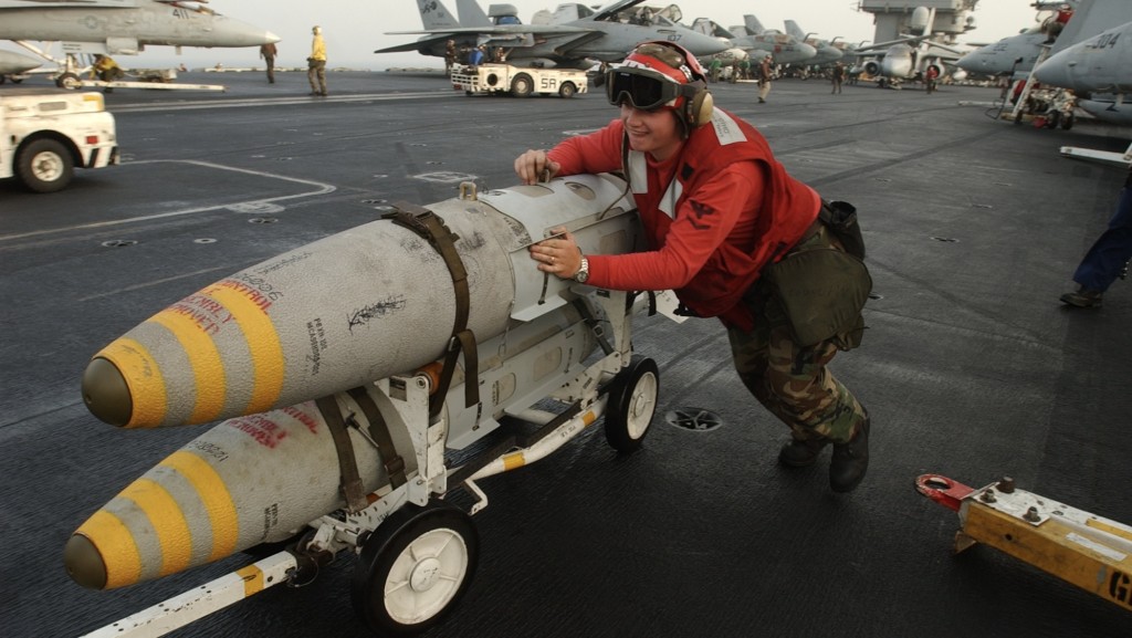一名航空兵將一車MK-82炸彈推向停泊在林肯號航空母艦飛行甲板上的F/A-18 大黃蜂。 美聯社