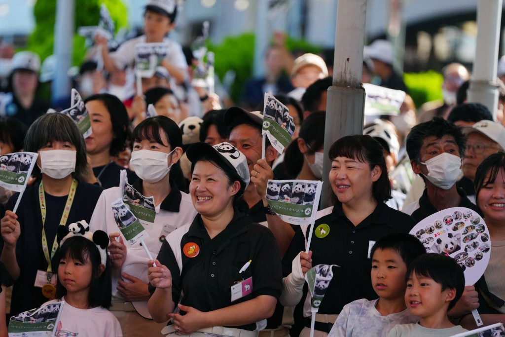 工作人員與當地民眾在日本和歌山縣冒險世界遊樂園外目送運輸大熊貓的運輸車離開。 新華社