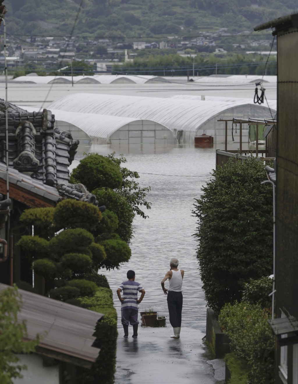日本南部福岡縣久留米市，民眾無奈看著房屋因大雨而被淹沒。AP