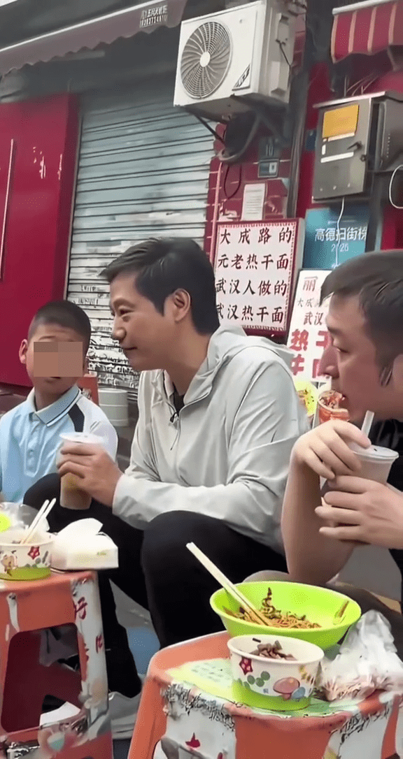 雷军武汉街头吃早餐，正与身边的小男孩聊天时，身后路过一名小女孩。