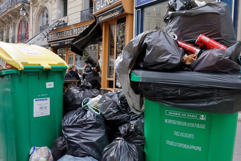 法國清潔工罷工10日，巴黎一家麵包店名外，垃圾堆至高過人頭。 路透社