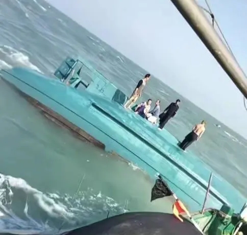 網傳視頻顯示，一船隻翻覆在海面上，船上站著數人正在等待救援。