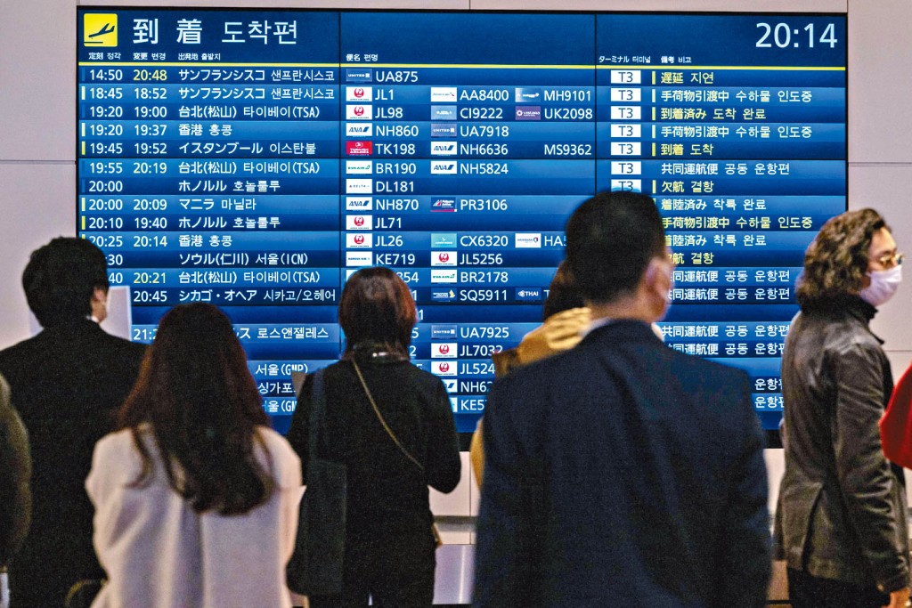 在东京羽田机场的乘客，观看航机班次的讯息。