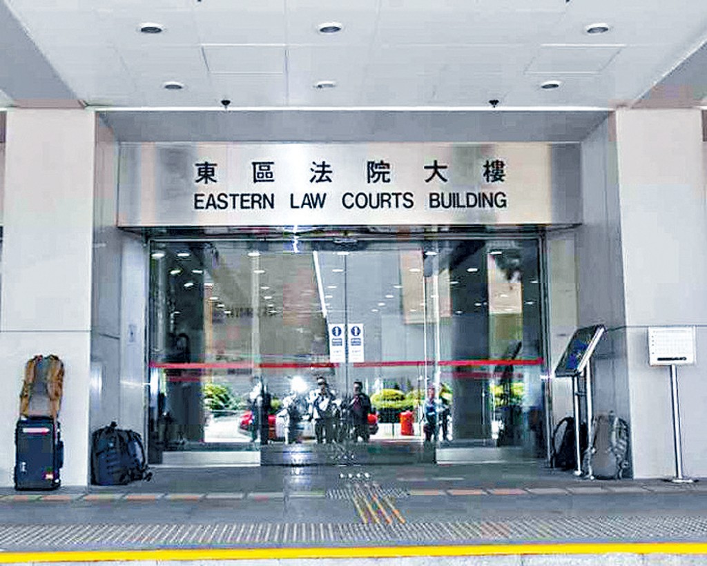 案件于东区裁判法院裁决，被告被押解到庭时，旁听席上的亲友向她挥手致意。
