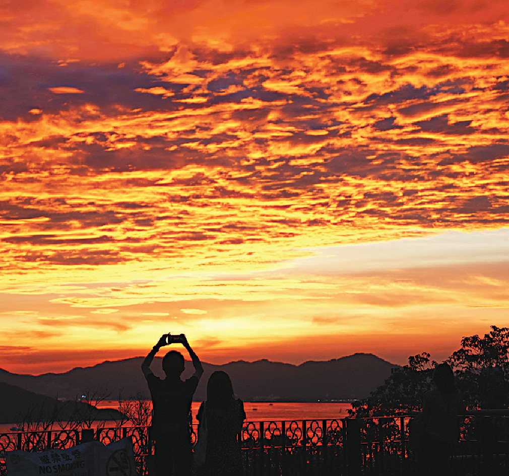 赤朱丹彤■七月曾出現黃昏「火燒雲」美景，市民爭相「打卡」留倩影。蘇正謙攝