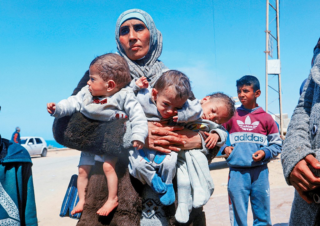 一名巴勒斯坦妇人带着3个营养不良的孩子，从加沙中部向南迁。