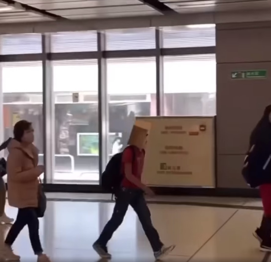 网民直击一名头笠纸袋的红衣乘客入闸后上电梯实况。网上截图