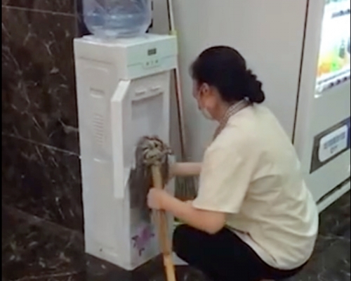 清潔女工用地拖擦拭飲水機。網圖