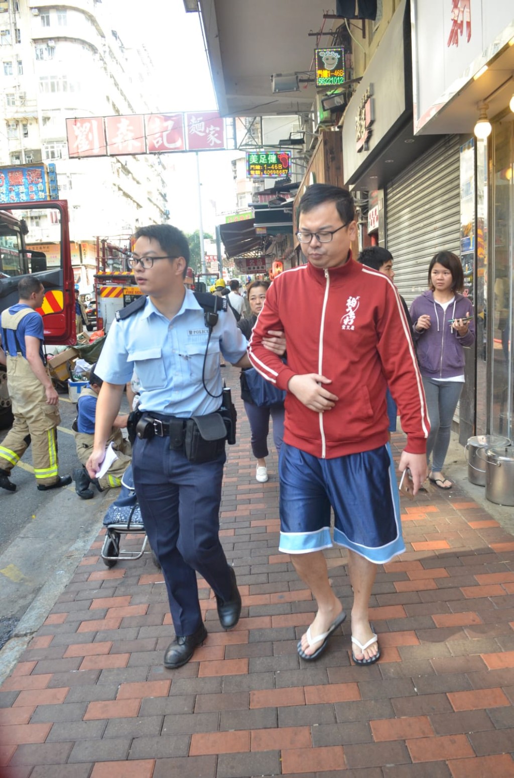 男住客吸入濃煙不適,警察協助上救護車。