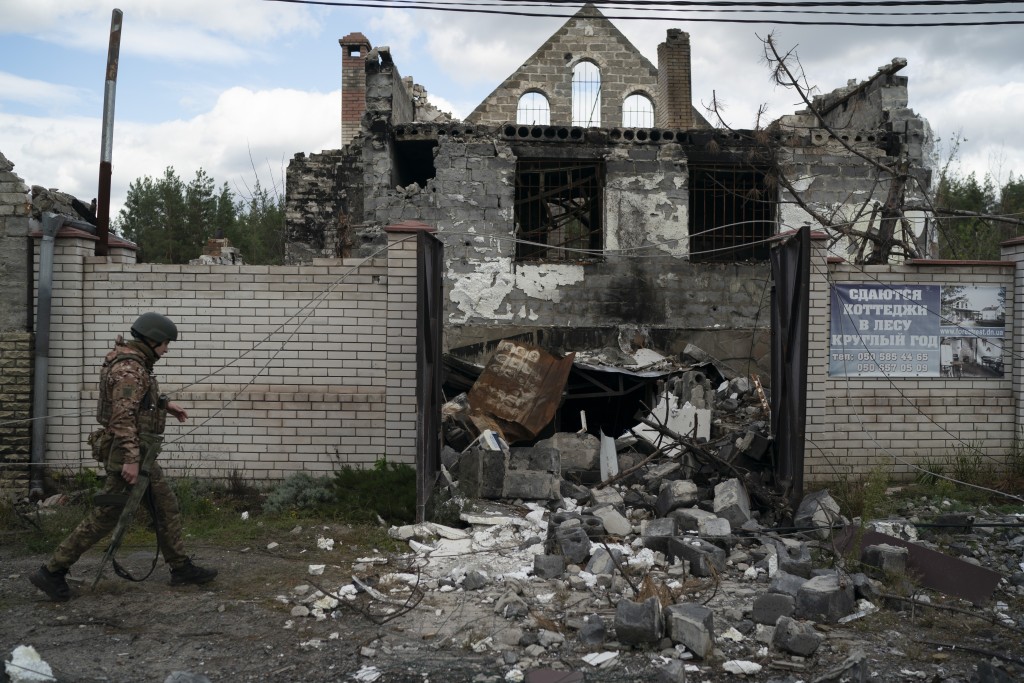 一名烏克蘭軍人走過重奪的村鎮內一座受損的建築物。AP