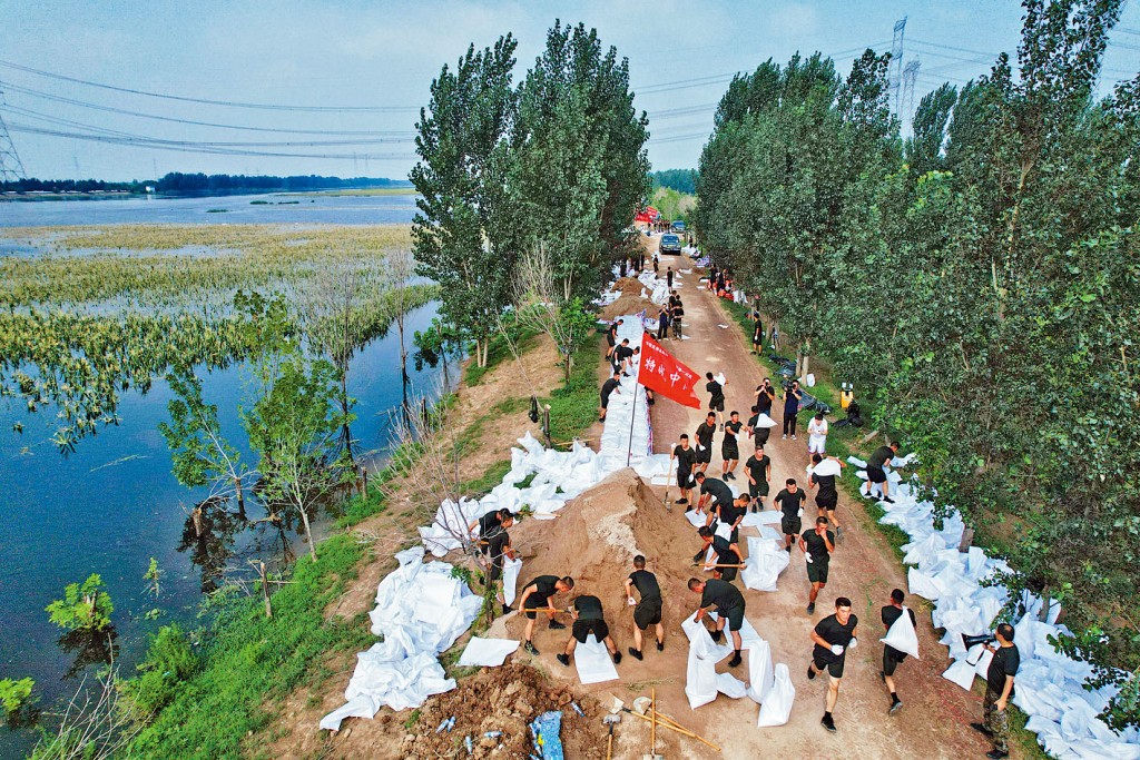 武警人员在天津静海区加高加固堤坝。
