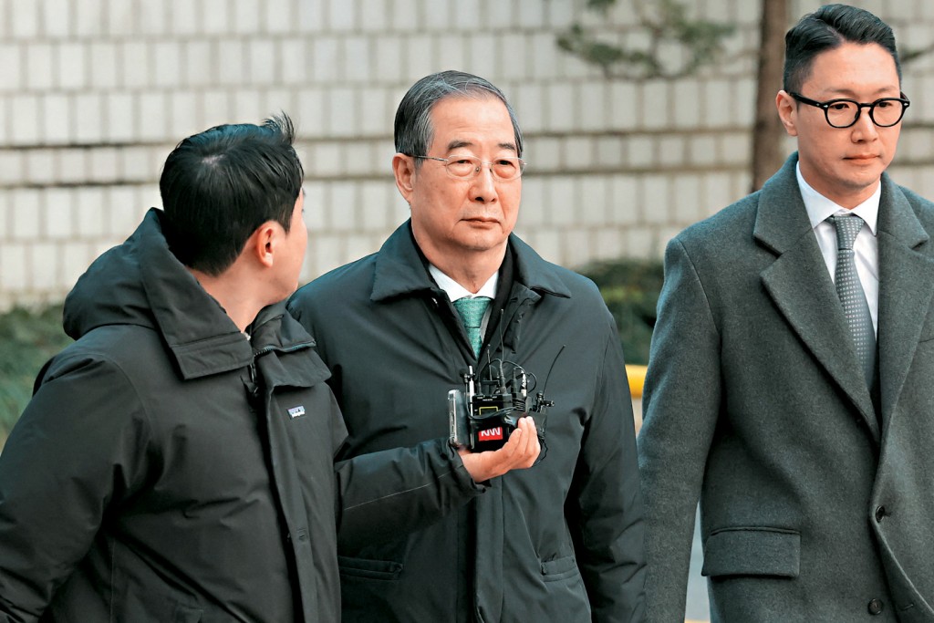 南韓前總理韓德洙(中)昨日到首爾法院聽判。 