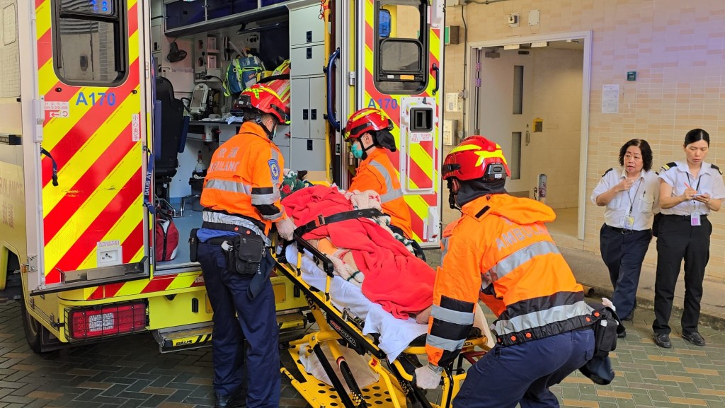 救护员将堕楼妇人送上救护车。