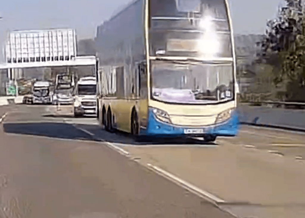 事發時故障城巴停在路中，後面停了一輛警車。(影片頻道「沿圖有理」提供)